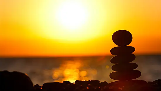 Balanced rocks with sun rise and water in the background