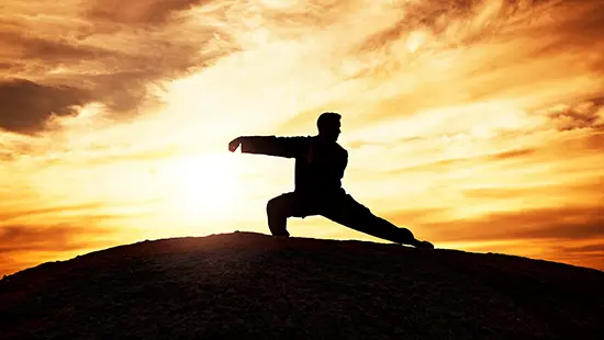 Tai Chi classes give balance - man on hill, in sunset